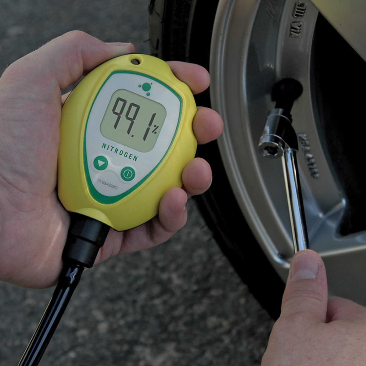 Person holding yellow MaxN2+ nitrogen analyzer to check tire